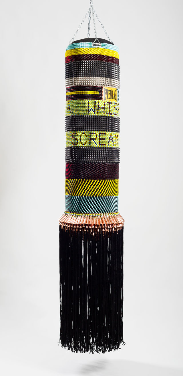Jeffrey Gibson. FROM A WHISPER TO A SCREAM, 2015. Found canvas punching bag, repurposed wool army blanket, glass beads, steel studs, artificial sinew, nylon fringe, copper jingles, steel chain, 79 1/2 x 18 x 18. Image courtesy of Jeffrey Gibson Studio. Photograph: Peter Mauney.