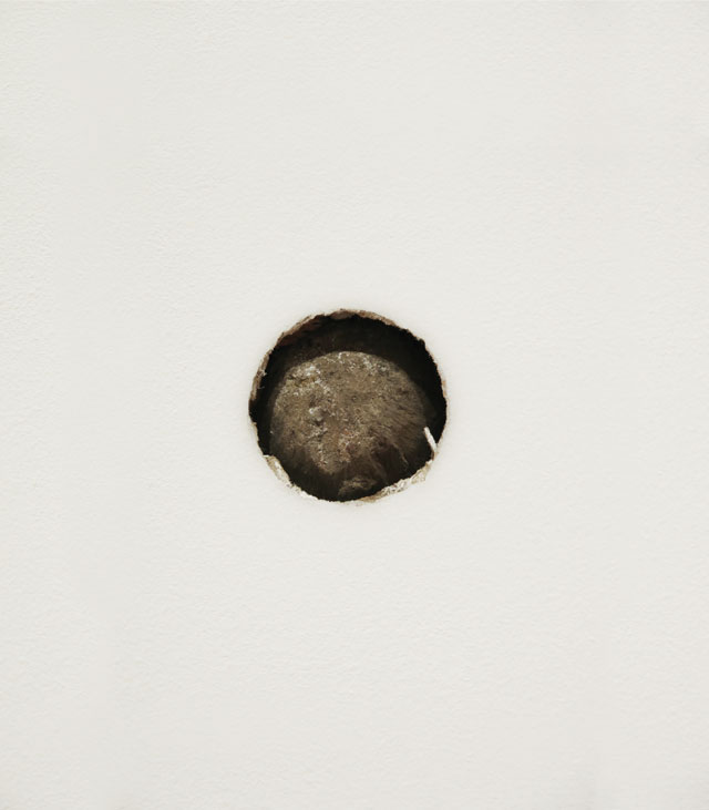 Peter Liversidge. Proposal for The Aldrich Museum No. 6: Re-enactment in the South Gallery of The Aldrich Museum of the Action that Caused a Cannonball to be Lodged in the North Façade of the Keeler Tavern, 2016. Three-pound lead cannonball, drywall, plywood, 2 1/2 x 2 1/2 x 3 1/2 in. © Peter Liversidge. Photograph: Tom Powel Imaging. Courtesy: Sean Kelly, New York.