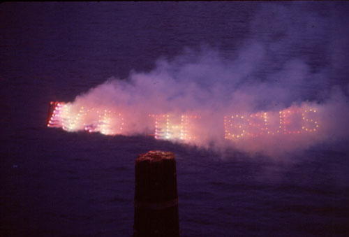 Dennis Oppenheim. Avoid the Issues, 1974. Red and green fireworks sign, potassium nitrate, 60 x 430 cm. Duration: one minute.
Location: looking east across East River to Brooklyn. 6.45pm, September. © Dennis Oppenheim.