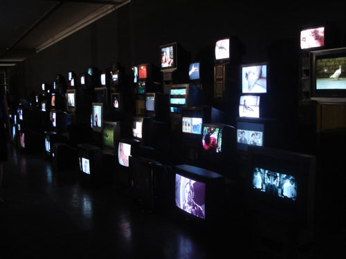 Douglas Gordon. <em>Pretty Much Every Film and Video Work From about 1992 Until Now to be Seen on Monitors, Some with Headphones, Others Run Silently, and all Simultaneously,</em> 1992–. Installation view.