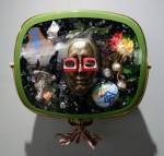 Nam June Paik. Self-Portrait, 1989. 1950s Philco Predicta TV cabinet containing bronze mask of the artist, videotape, antigue TV tubes, circuit board. eggs, painted globe, watch, suspenders, pewter Buddha, magnet, painted toy piano, I-Ching page, silk flower, 1 pair of eye glasses. Edition of 12. 24 x 27 x 16 in. Carl Solway Gallery.