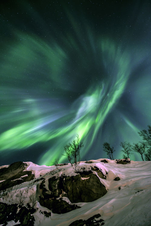 EARTH AND SPACE. Runner Up: Fredrik Broms (Norway), Green Energy. The shifting lights of the Aurora Borealis can take on many shapes and forms as they are moulded by the Earth’s complex magnetic field. Sheets and planes of glowing gas appear to be twisted into a giant vortex above Grøtfjord in Norway. © Fredrik Broms.