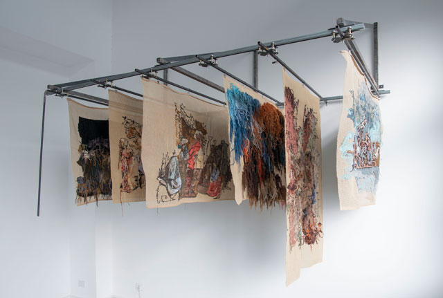 Bertille Bak. Rayonnage, 2009-14. Supporting structure made of iron, six embroideries (wool on canvas, 90 x 130 cm each) and iron rod to move the canvases. Installation view at The Gallery Apart, Rome. Collection EMST National Museum of Contemporary Art, Athens, Greece. Photo: Giorgio Benni.