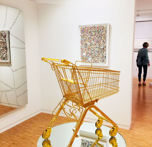 Sylvie Fleury, Serie ELA 75/K (Easy, Breezy, Beautiful) 2000. Gold-plated shopping cart and plexiglas bared aluminium pedestal on turning mirror and aluminium pedestal. Installation view, The Bunker Artspace, West Palm Beach, Florida. Photo: Jill Spalding.