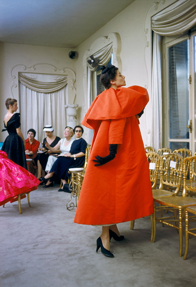 Model wearing Balenciaga orange coat as I. Magnin buyers inspect a dinner outfit in the background, Paris, France, 1954 © Mark Shaw, mptvimages.com