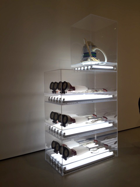 Jeff Koons. New Hoover Deluxe Shampoo Polishers, New Shelton Wet/Dry 5-Gallon Displaced Quadradecker, 1981-87. Six shampoo polishers, vacuum cleaner, acrylic and flourescent lights. Photograph: Jill Spalding.