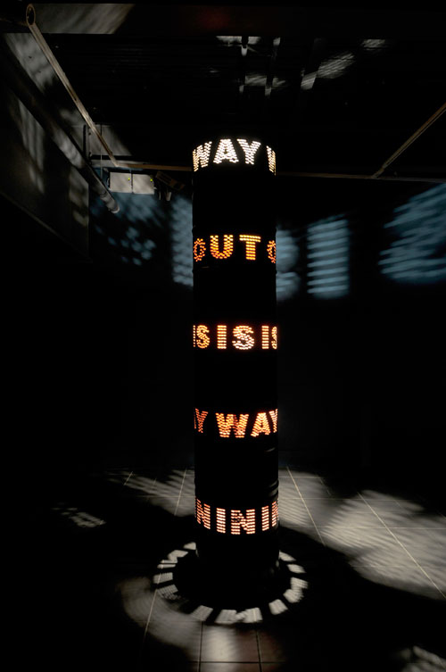 Liliane Lijn. Way Out Is Way In, 2009 (view 2). Painted steel solvent drums, 3 phase motor, inverter and programmed speed and direction control chip, halogen lighting, 300 x 60 cm. Photograph © the artist.