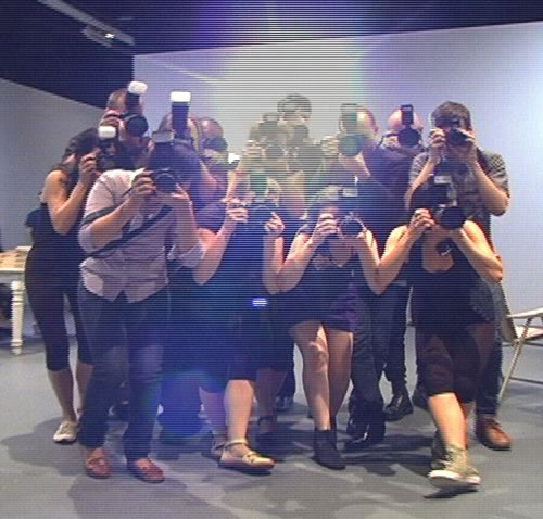 Xavier Cha. Ring. 2010. Courtesy of The Kitchen's Archive. A formation of photographers mechanically move through The Kitchen gallery intently focusing and shooting an absent subject.