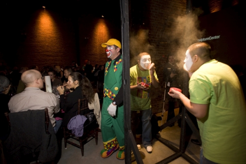 Xavier Cha. Clown Gala, 2007. Two-way mirrors, professional clowns. Men and women transform from pedestrian dress to fully fledged clowns in front of two-way mirrors during the Sculpture Center Winter Gala honouring Jenny Holzer. Art event becomes voyeuristic clown factory.