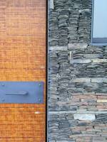 A close-up of the roof-tile wall interplay with bricks, and the steel-framed door with bamboo fascia veneer.