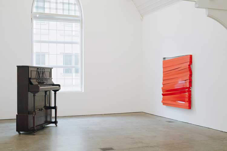 Angela de la Cruz, Upright Piano, 1999 (left), and Shutter (Red), 2017. Installation view, UPRIGHT, Ikon Gallery, Birmingham, 2026. Image courtesy Ikon. Photo: Tom Bird.