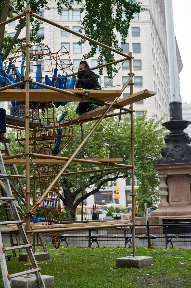 Abigail DeVille installing ​Light of Freedom in Madison Square Park, 2020. Welded steel, cabling, rusted metal bell, mannequin arms, metal scaffolding, wood, 156 x 96 x 96 inches approximately. Collection the artist. Madison Square Park Conservancy, New York. Photo: Andy Romer.