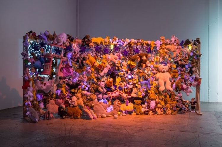 Abigail DeVille. Wave Wall I​, 2018. Fabric scraps; wood; metal chain-link fencing; Good Will toys from Portland, Oregon; metal bells; stuffed animals; disco ball; electric doll, 180 x 36 x 96 inches. Courtesy the artist. Photo: Evan LaLonde.