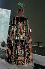 Abigail DeVille. Haarlem Tower of Babel​, 2012. Reclaimed lumber, accumulated debris from Dead Horse Bay, my grandmother’s heirlooms, charcoal, mannequin legs, American flag painting, zip ties, shopping cart, milk crates, 72 x 72 x 192 inches. Courtesy the artist. Photo: LaToya Ruby Frazier.