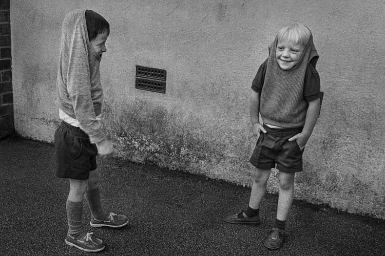 Markéta Luskačová, Two boys with their jumpers over their heads, Booker Avenue primary school, Liverpool, 1988. © Markéta Luskačová.
