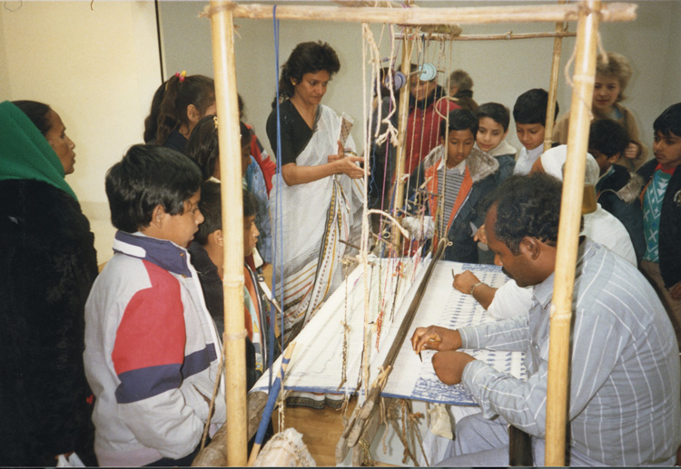Children taking part in workshops with master weavers Haji Kafiluddin Bhuiya and Nurul Islam during the exhibition Woven Air: The Muslin and Kantha Tradition of Bangladesh, 4 March – 1 May 1988, Whitechapel Gallery. Whitechapel Gallery Archive.