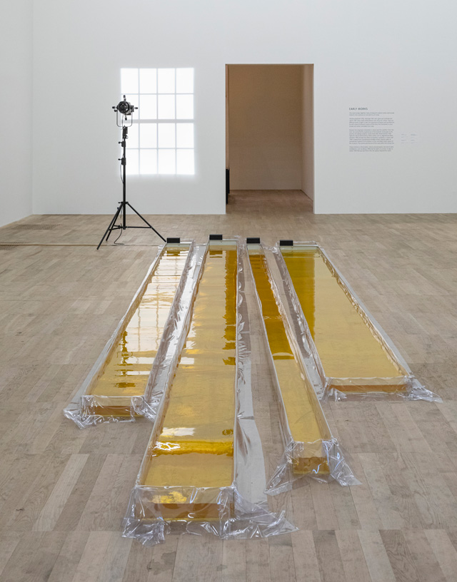 Olafur Eliasson. Wavemachines, 1995. Acrylic, transparent plastic sheet, water, ink (yellow), motors, transformer, 25 x 900 x 212 cm. Installation view, Tate Modern, London, 2019. Photo: Anders Sune Berg. Kunstmuseum Basel. © 1995 Olafur Eliasson.