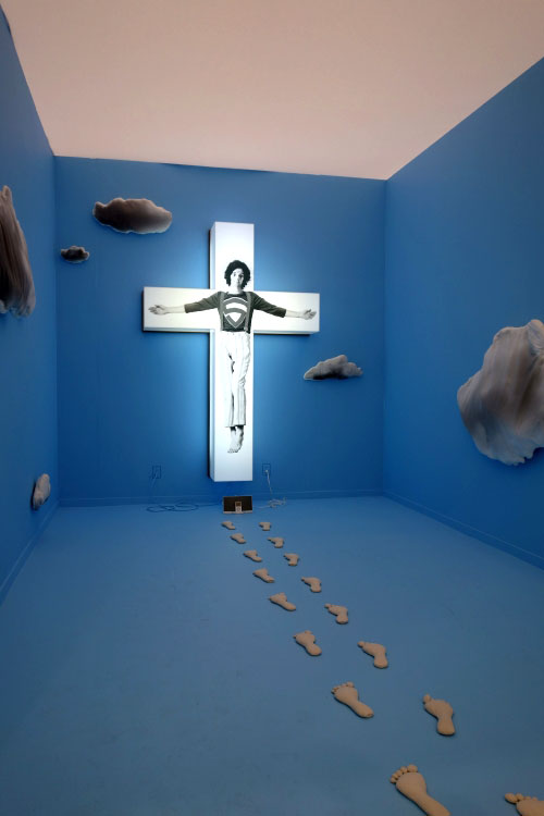 Jack Early. WWJD. Cross, footprints, clouds, original audio track: Hey Jesus, 2012. Printed Lexam, lights, plywood, muslin, lentils, printed cotton. Various Dimensions.