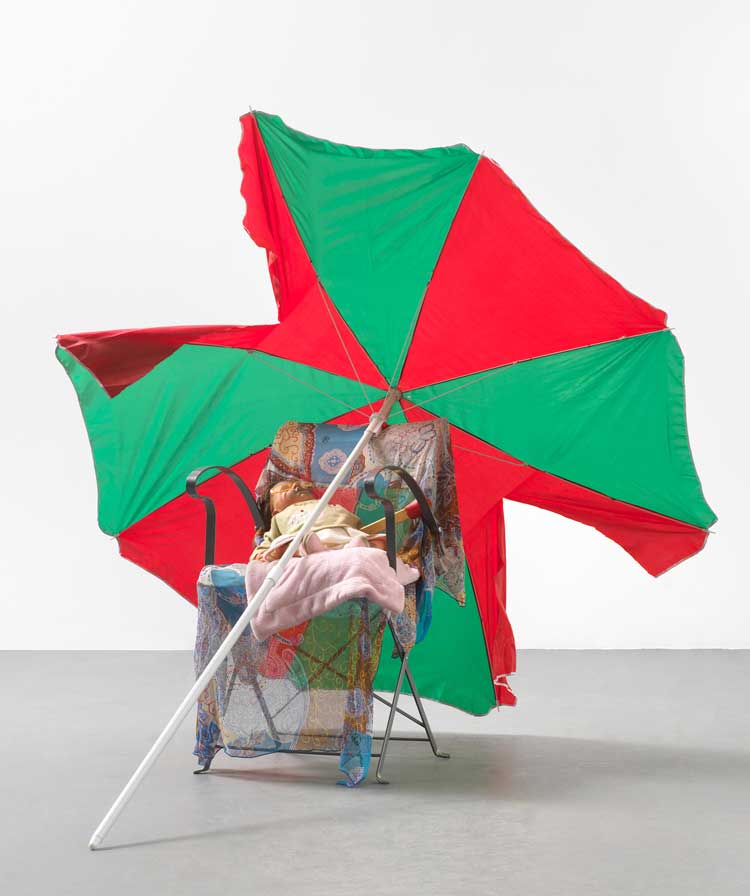 Isa Genzken, Untitled, 2006. Folding chair, doll, blanket, fabric, glasses, plastic, lacquer, spray paint, sunshade, approx 148 x 176 x 160 cm. Hauser & Wirth, David Zwirner. Courtesy Galerie Buchholz © VG Bild-Kunst, Bonn 2023.