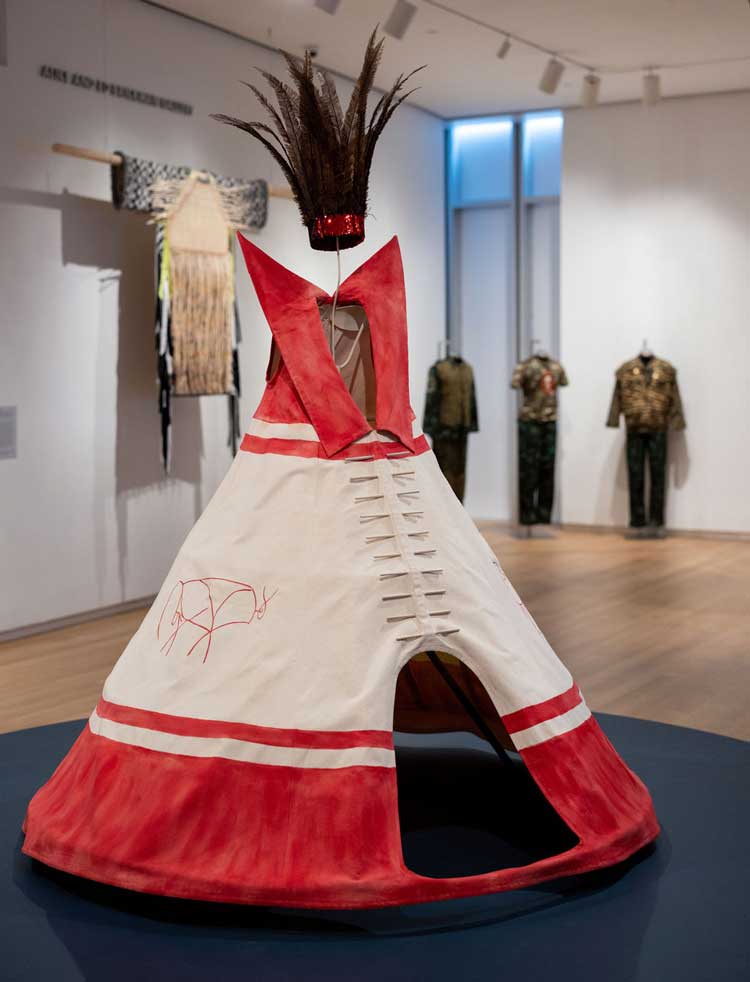 Kent Monkman. Foreground: Miss Chief’s Tipi Dress (Red), 2020; Background: (l): Jeffrey Gibson,The Anthropophagic Effect, Garment no. 4, 2019; ( r): Jakkai Siributr. Blind Faith I, II, III, 2011/2019. Photo by Jenna Bascom; courtesy the Museum of Arts and Design.