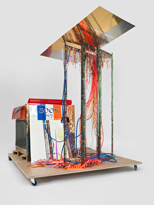 Isa Genzken. Disco Soon (Ground Zero), 2008. Synthetic polymer paint on plastic, cardboard, mirror, spray paint, metal, fabric, hose lights, mirror foil, printed sticker, wood blocks, fiberboard, and casters, 219 x 205 x 165 cm. Carlos and Rosa de la Cruz Collection. Courtesy the artist and Galerie Buchholz, Cologne/Berlin. © Isa Genzken