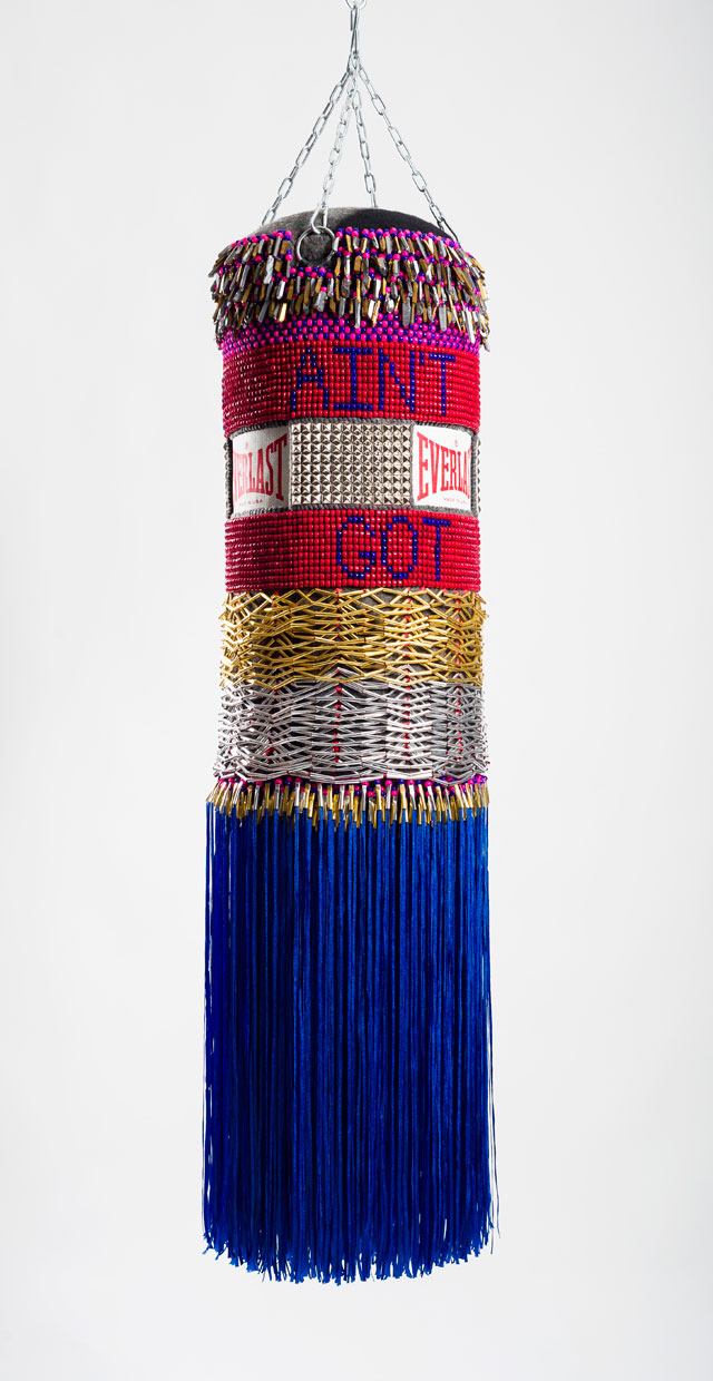 Jeffrey Gibson. AIN'T GOT NO, I GOT LIFE, 2014. Found canvas punching bag, repurposed wool army blanket, glass beads, plastic beads, steel studs, artificial sinew, nylon fringe, tin cones, quartz crystals, steel chain, 55 x 15 x 15 in. Image courtesy of Jeffrey Gibson Studio. Photograph: Peter Mauney.