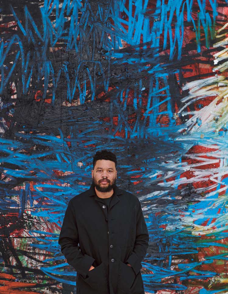 Oscar Murillo in front of his painting manifestation, 2020-22. Oil, oil stick, graphite, and spray paint on canvas and linen, 349.9 × 480.1 cm (137 ¼ × 189 in). Photo: Jason Schmidt © Oscar Murillo. Courtesy the artist and David Zwirner.