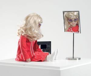 Lynn Hershman Leeson. CyberRoberta, 1996. Custom-made doll, clothing, glasses, webcam, surveillance camera, mirror, original programming, and telerobotic head-rotating system, approximately 17 ¾ x 17 ¾  x 7 ⅞  in (45 x 45 x 20 cm). Courtesy the artist; Bridget Donahue Gallery, New York; and Altman Siegel, San Francisco.