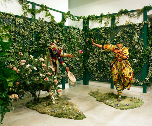 Yinka Shonibare MBE. <em>The        Pursuit</em>, 2007. Two life-sized mannequins, Dutch waxed printed cotton, shoes, coir matting, artificial silk flowers, mixed media, male

      figure 162 x 161 x 200 cm; female figure: 169 x 190 x 140 cm. Rabo Art Collection. Commissioned by the Musée du Quai Branly for the      exhibition Jardin d’Amour 2007. Courtesy of the artist and Stephen Friedman Gallery © the artist. Parasol unit installation view. Photo Stephen White.