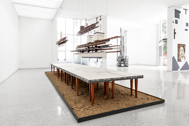 Remy Jungerman. Visiting Deities, 2018-19. Cotton textile, kaolin, dry river clay, water samples, painted wood, 58 table legs (meranti), yarn, mirror and nails, 384 x 138 x 102 in (975 x 350 x 260 cm). Photo: Aatjan Renders.