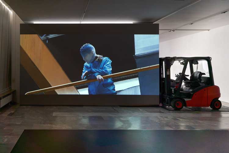 La Horde, Novaciéries, 2015. Single-channel video installation; projection wall, forklift, dance mats, video, 16′48′′, colour, sound. Dimensions variable. Installation view, (LA)HORDE, JSF Berlin. Photo: Alwin Lay.