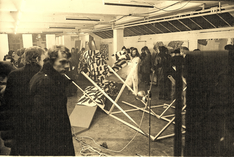 Ian Breakwell in white overalls begins wrapping the sculptures with paper covered in the words UNSCULPT, at the New Arts Lab, 1970. Photo courtesy Mike Leggett.