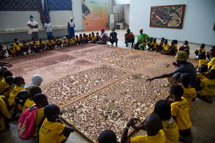 The artistic director of SCCA Tamale Selom Kudjie guiding school children through one of the exhibitions at Red Clay Studio. © Ibrahim Mahama. Photo courtesy of the SCCA and Red Clay, Tamale.