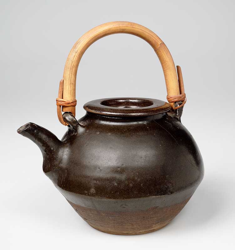 Teapot with a tenmoku glaze and bamboo handle, unknown maker, Japan, 1934. From the collections of the Crafts Study Centre, University for the Creative Arts.