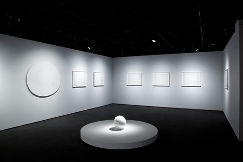 Mariko Mori. FOREGROUND: Tama I, 2011. Epoxy with pearlescent finish; 13 inches diam. BACKGROUND (LEFT TO RIGHT): White Hole VII, 2009. Mixed media on plexiglass panel; 50 × 55 inches. Higher Being no. 35, 2009. Mixed media on paper; 20 × 30 inches. Collection of Mr. and Mrs. Wilbur L. Ross. White Hole no. 47, 2008. Mixed media on paper; 22 × 30 inches. Faou no. 9, 2010. Mixed media on paper; 22 × 30 inches. Faou no. 21, 2010. Mixed media on paper; 22 × 30 inches. Higher Being no. 12, 2009. Mixed media on paper; 22 × 30 inches. Faou no. 43, 2010. Mixed media on paper; 22 × 30 inches. Courtesy of SCAI THE BATHHOUSE, Tokyo and Sean Kelly, New York. Installation photograph by Richard Goodbody.