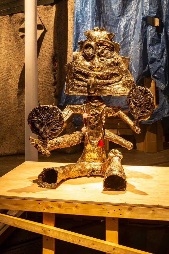 Ramesh Mario Nithiyendran. Seated Bronze Figure with Masks, 2023. Cast bronze, beads, 136 x 104 x 95 cm. Photo courtesy Tramway.