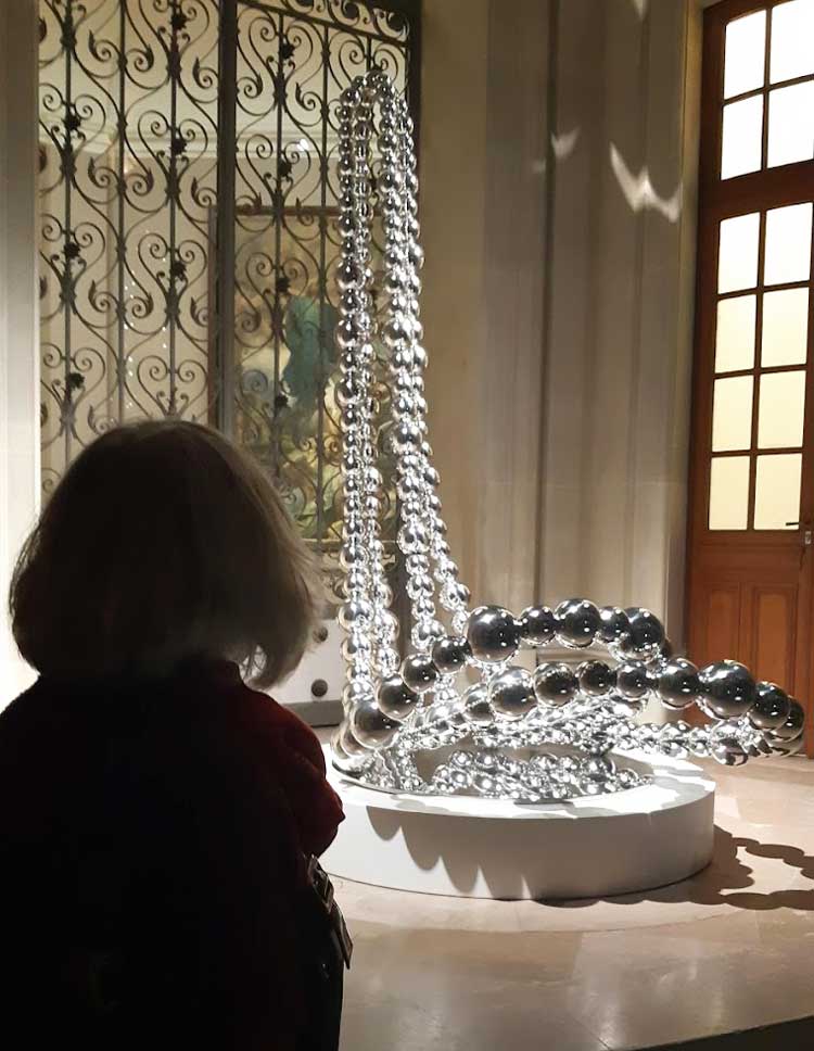A visitor at Petit Palais observes one of Othoniel’s giant necklaces. Installation view, Jean-Michel Othoniel: The Narcissus Theorem, Petit Palais, Paris 2021. Photo: Ana Beatriz Duarte.