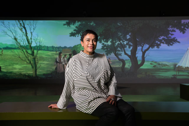 Lisa Reihana, in front of in Pursuit of Venus (infected), 2015-17, Oceania exhibition, Royal Academy of Arts, London, 29 September – 10 December 2018 © Auckland Art Gallery Toi o Tāmaki, gift of the Patrons of the Auckland Art Gallery, 2014. Additional support from Creative New Zealand and NZ at Venice Patrons and Partners © courtesy of the artist and ARTPROJECTS. Photo: David Parry.