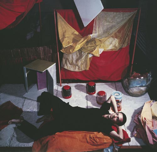 Hélio Oiticica with <em>Bólides</em> and <em>Parangolés</em> at his atelier at Engenheiro Alfredo Duarte Street, Rio de Janeiro, c.1965 AHO/ PHO, RJ. (c) Projeto Hélio Oiticica