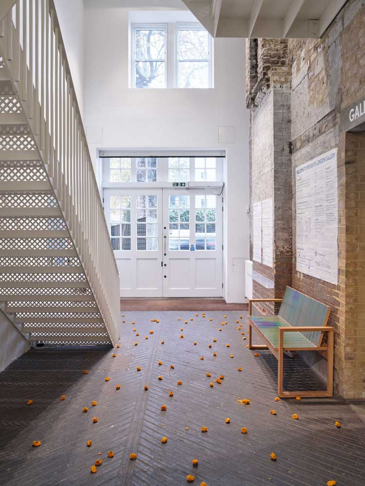 Marigolds scattered across the Fire Station entrance. Installation view, William Pope.L: Hospital, South London Gallery, 21 November 2023 – 11 February 2024. Photo: Andy Stagg.