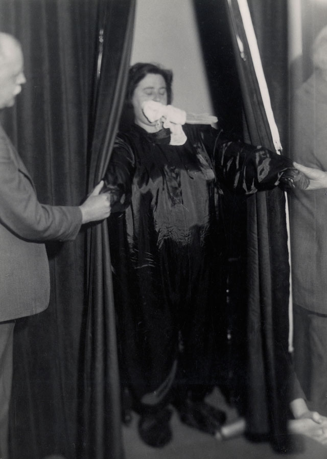 Helen Duncan emerging from curtains with ‘ectoplasm’ – her hands holding those of others
at the séance, Edinburgh, 1933. Photograph © Senate House Library, University of London.