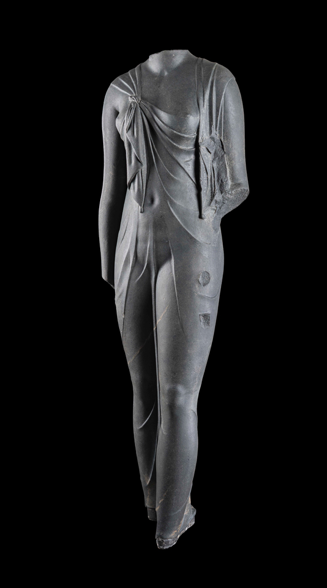 Statue of Arsinoe, Canopus, Aboukir Bay, Egypt (SCA 208). Cut in hard, dark stone, this feminine body has a startlingly sculptural quality. Complete, it must have been slightly larger than life-size. The statue is certainly one of the queens of the Ptolemaic dynasty (likely Arsinoe II) dressed as the goddess Isis, as confirmed by the knot that joins the ends of the shawl the woman wears, which was representative of the queens during this time period. The statue was found at the site of Canopus. © Franck Goddio/Hilti Foundation. Photograph: Christoph Gerigk.