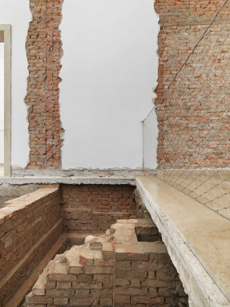 Maria Eichhorn, Relocating a Structure. German Pavilion 2022, 59th International Art Exhibition – La Biennale di Venezia, 2022, detail: Foundations of the rear wall from 1909; rear wall of the building from 1909, interior wall from 1938, demolished in 1964; wall lettering; chimney from an earlier building (undated); doorway to the right side room from 1909, walled up in 1912, exhibition view, © Maria Eichhorn / VG Bild-Kunst, Bonn 2022, photo: Jens Ziehe.