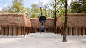 Simone Leigh, Façade, 2022. Thatch, steel, and wood, dimensions variable. Satellite, 2022. Bronze, 24 × 10 × 7 ft 7 in (7.3× 3 × 2.3 m) (overall). Courtesy the artist and Matthew Marks Gallery. Photo by Timothy Schenck. © Simone Leigh.