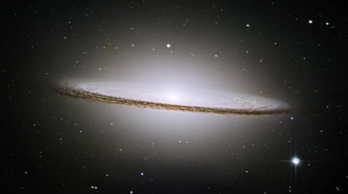 The Sombrero Galaxy (M104). Hubble Space Telescope, 2003. Advanced Camera for Surveys (ACS). Like other spiral galaxies, the Sombrero consists of a flat disc of stars surrounding a fatter central ‘bulge’. However, here this central core of stars extends out to encompass the whole of the disc in a halo of stars. Like most galaxies, the heart of the Sombrero conceals a dark secret: a super-massive black hole containing as much matter as a billion Suns. © NASA and the Hubble Heritage Team (STScI/AURA): http://hubblesite.org/gallery/album/pr2003028a/